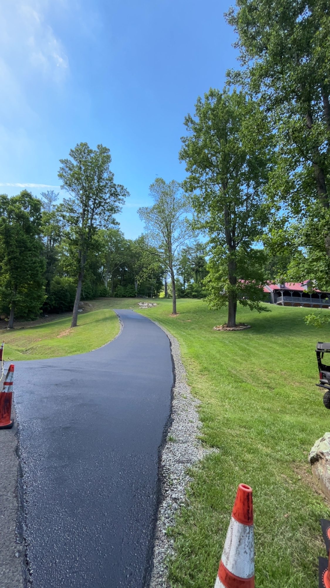 Curved sealcoated driveway through a green lawn